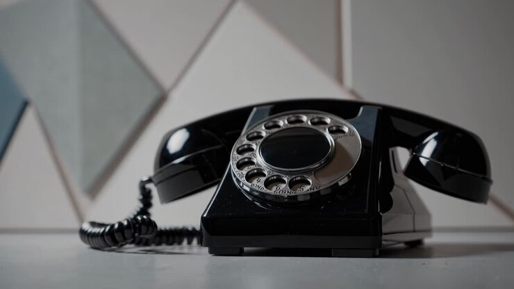 Photo en contre-plongée d’un téléphone rotatif vintage sur une table, avec un arrière-plan géométrique