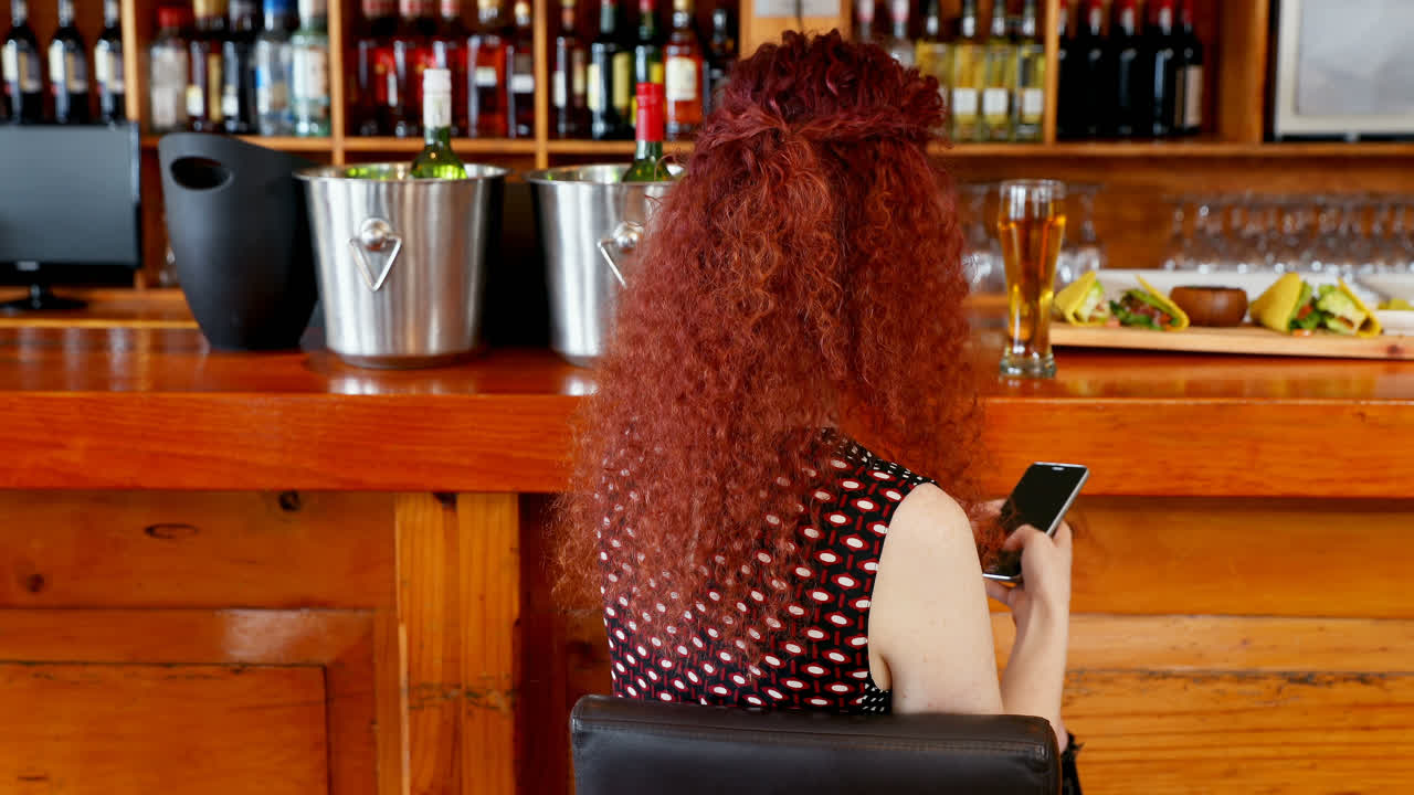 mujer usando teléfono móvil en el bar 4k