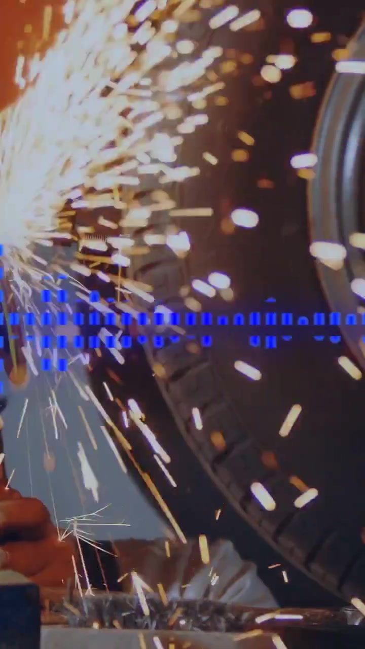 Vertical video: On grinder contact mechanic grinding edge, sending sparks to wheel, blue overlay