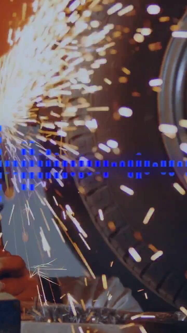 Vertical video: On grinder contact mechanic grinding edge, sending sparks to wheel, blue overlay