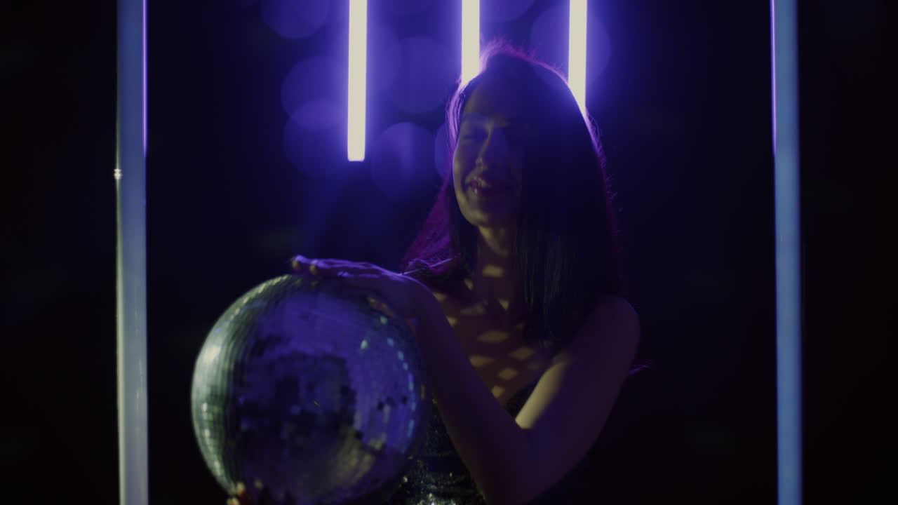 Donna con palla da discoteca sotto luce al neon