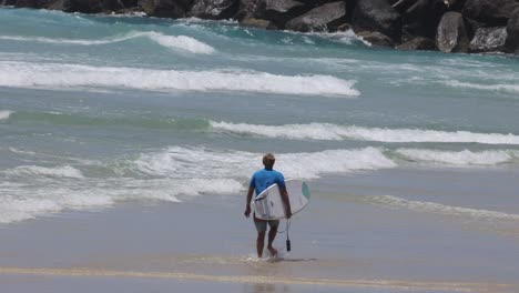 surfer walking towards the sea with surfboard