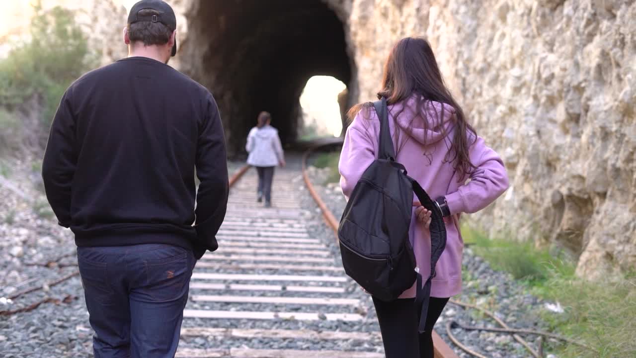 People walking on abandoned railway. Forgotten paths hiker group of backpacker friends. Hiking adventure in nature.