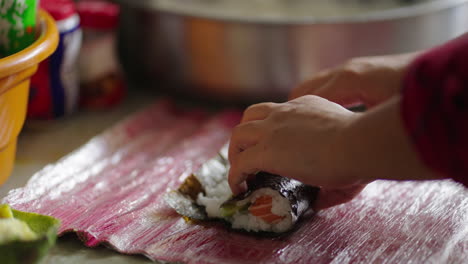 chef carefully lays sliced fish over rice as part of sushi roll assembly in kitchen scene, forms and rolls carefully