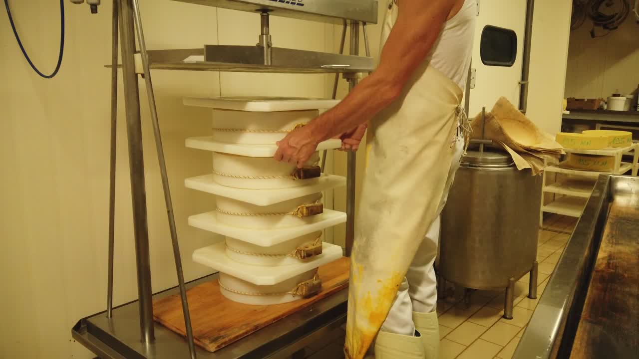 Close up of a man at work pressing cheese in a dairy