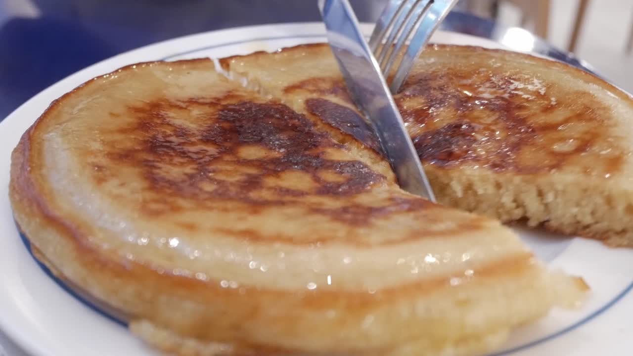 Golden-brown pancake sliced and drizzled with syrup, close-up view showcasing its texture