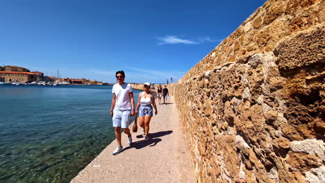 people through the walkway at the old lighthouse in the harbor of chania, crete, greece. pov shot