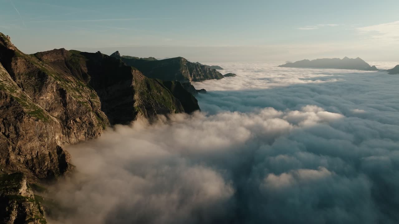 Sunrise aerial showing alpine cliffs surrounded by rolling clouds in Melchsee-Frutt, Switzerland
