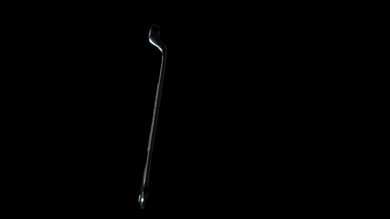 una llave inglesa o una llave inglesa girando frente a un fondo negro, cerrada y abstracta