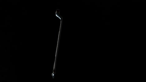 una llave inglesa o una llave inglesa girando frente a un fondo negro, cerrada y abstracta