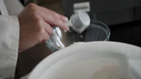 person takes white clean powder with a spoon out of a bucket