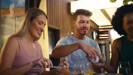 grupo de amigos multiculturales sonrientes desayunando al aire libre en casa juntos