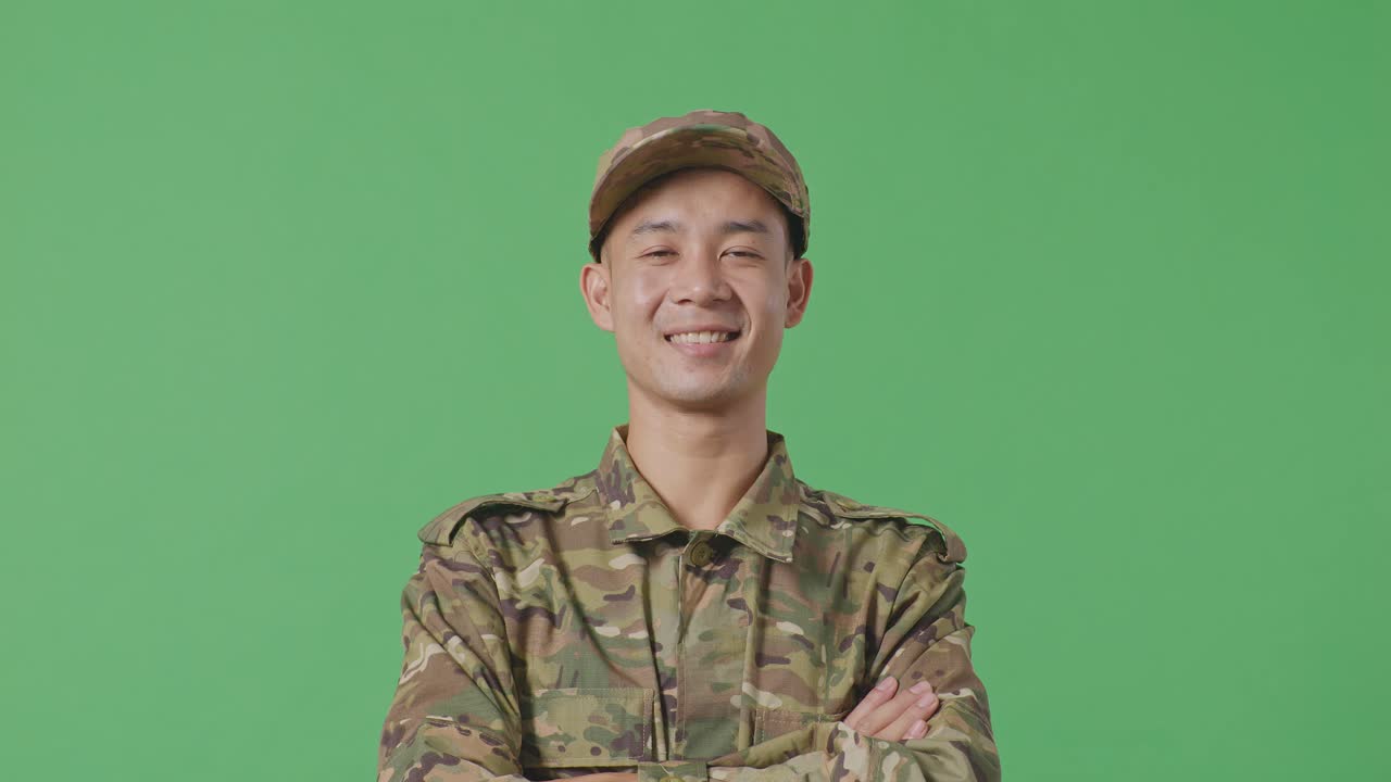 Close Up Of Asian Man Soldier Smiling And Crossing His Arms While Standing In The Green Screen Background Studio