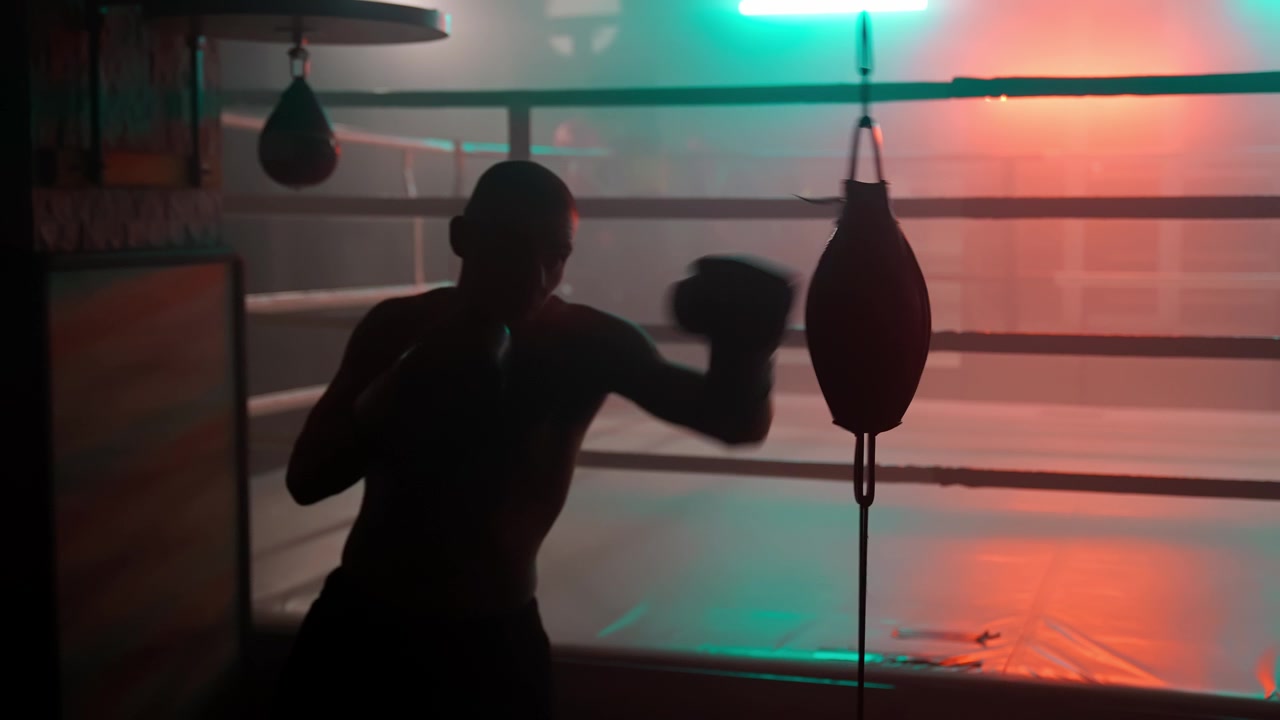 Silhouette di un pugile che si allena con il sacco veloce in una palestra buia con luci al neon