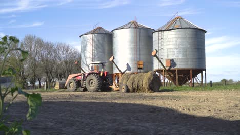 trattore rosso da silos di grano in una fattoria soleggiata, cielo limpido, colpo statico