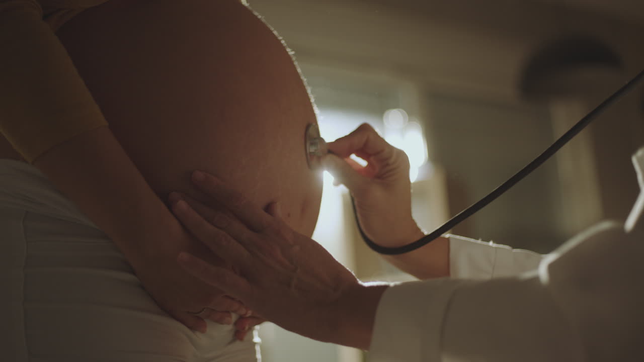 Medico che visita la pancia di una donna incinta con lo stetoscopio
