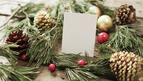 video of christmas decorations and white card with copy space on wooden background