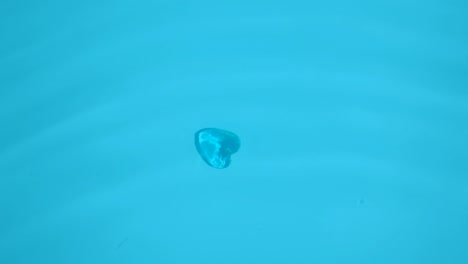 una joya en forma de corazón se encuentra en el fondo del mar con agua azul.