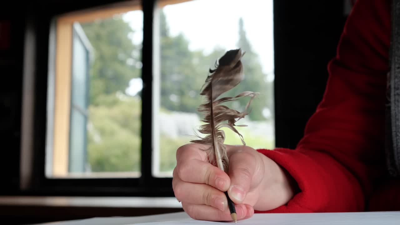 Mano di donna che scrive con una penna a calamo all'interno di una baita nel bosco - primo piano.