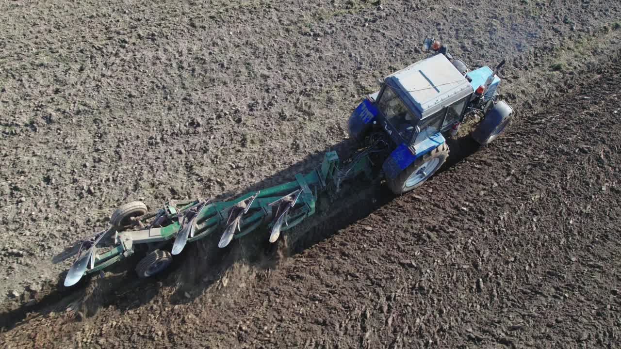 Tractor with a trailed plow cultivating the soil in season