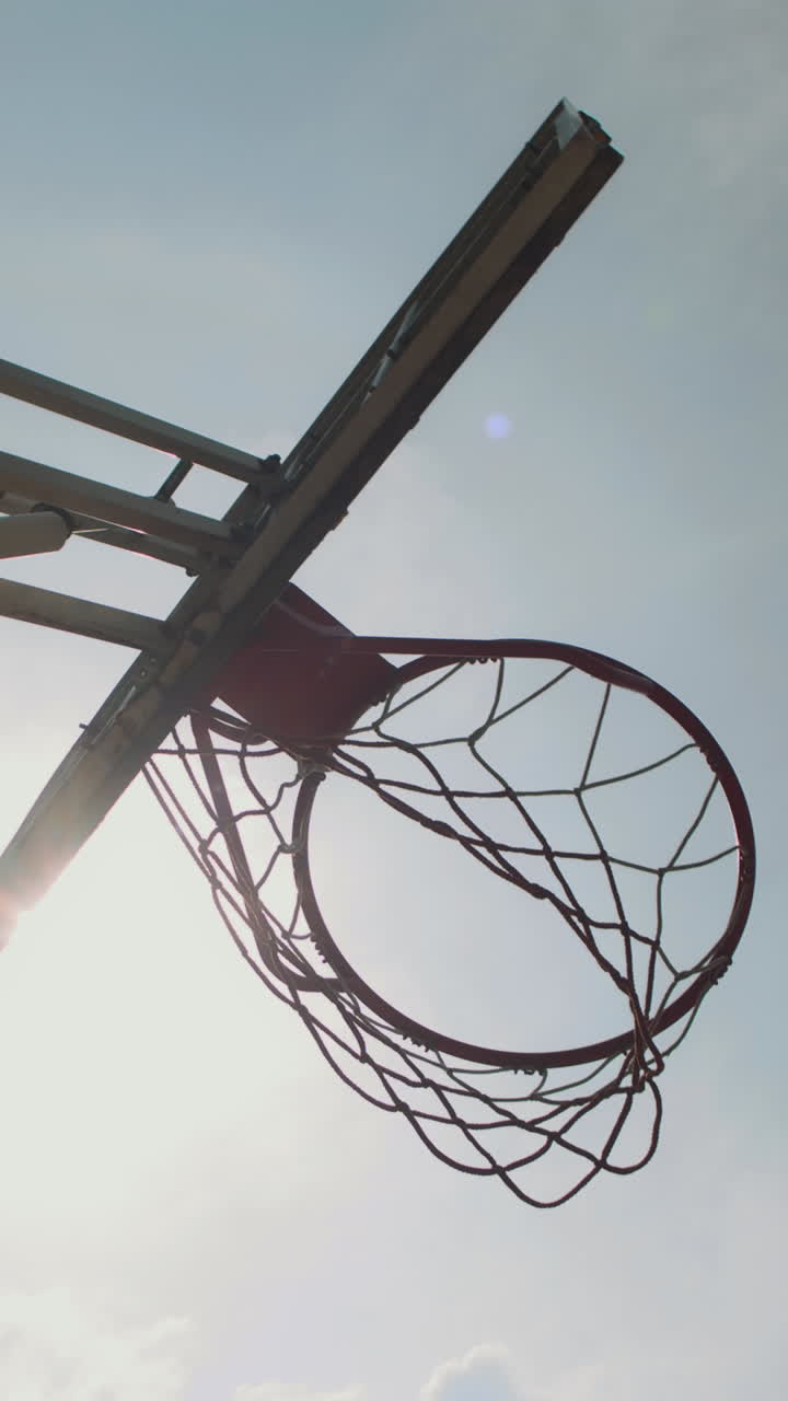 Vertical of Streetball Ring with Net and Ball against Sky