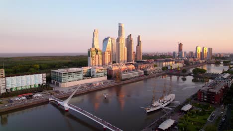 vista aérea del puente de la mujer con los rascacielos de lujo de puerto madero al atardecer, buenos aires, argentina