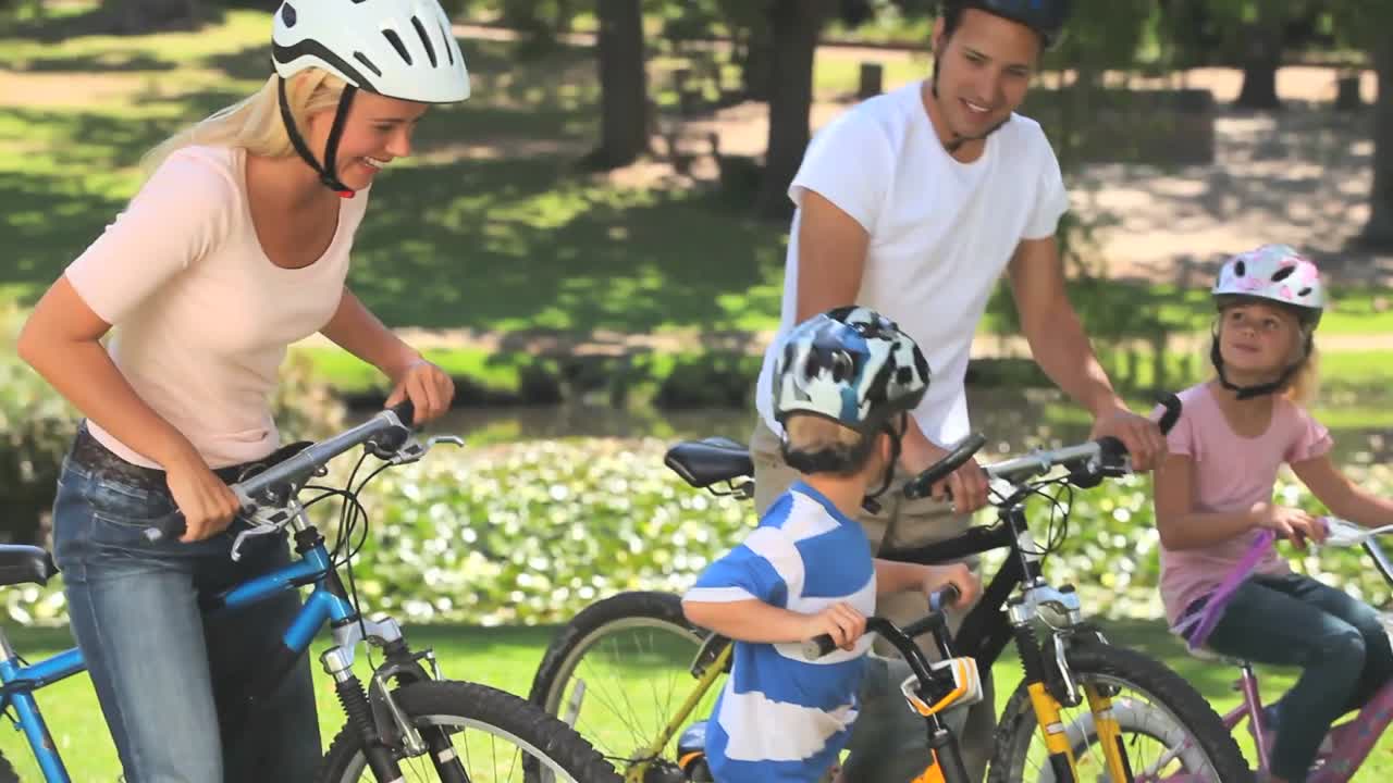 젊은 부부 가 두 자녀 와 함께 자전거 를 타고 있다