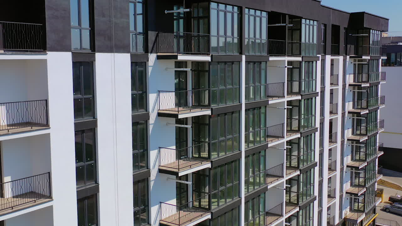 Newly built urban architecture. Exterior of residential building in the city. Modern building with tall glass windows and balconies.