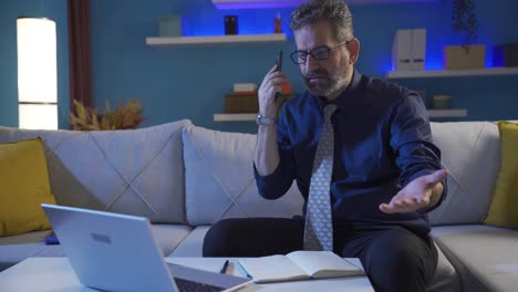 Businessman-working-late-at-night-talking-on-the-phone-and-feeling-angry.