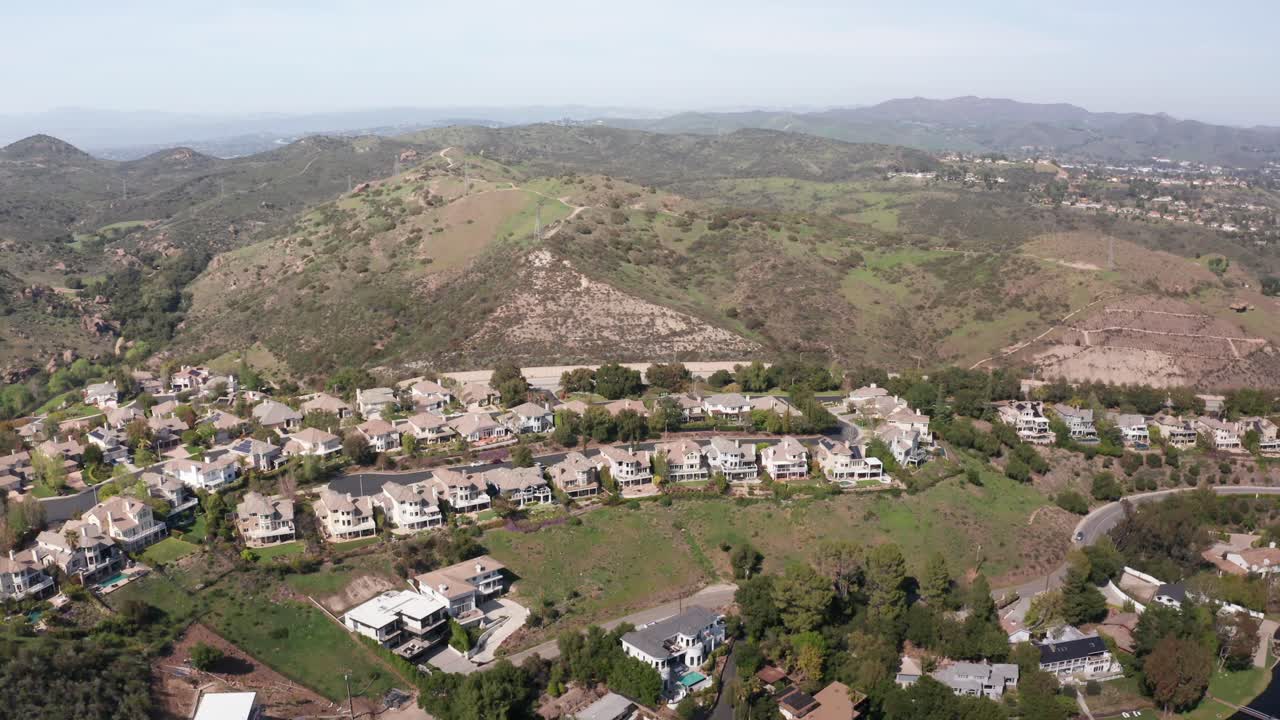 Wide reverse pullback aerial shot of an exclusive gated community in Lake Sherwood, California. 4K at 30 FPS