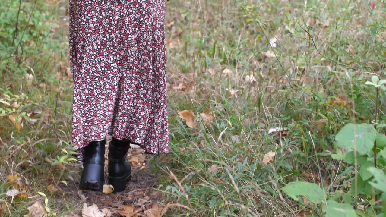 가을 숲에 있는 브루네트 소녀는 길을 걷고 머리를 움켜쥔다