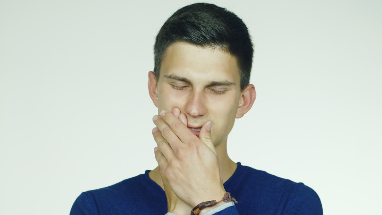 흰색 배경에 있는 스튜디오에서 촬영한 비디오 - 한 남자가 치통이 있고 통증이 미소로 사라집니다.