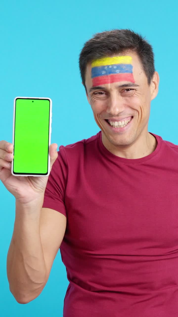 Venezuelan supporter looking at his mobile smiling and showing it