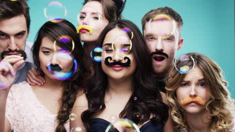 friends having fun with mustaches and bubbles