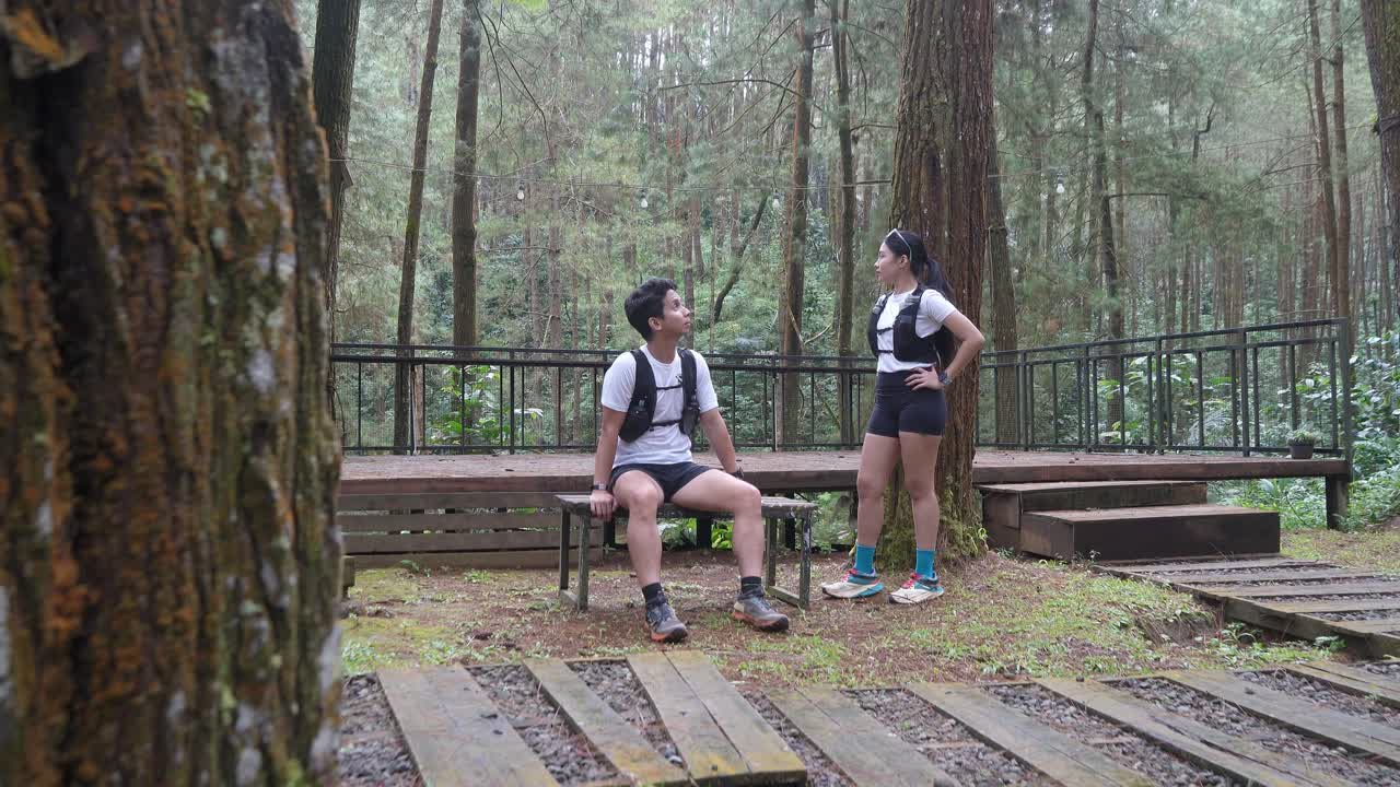 Asian couple taking photo with smartphone during outdoor trail run in Indonesian forest