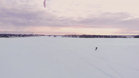 slow motion: a male athlete is engaged in kiting on skis. he rolls on the ice of a large lake. rolling, he performs various jumps, coups and other exercises. windy sunny winter day