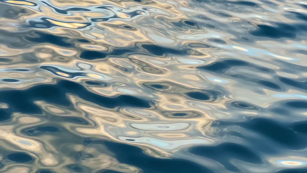 La superficie dell'acqua riflette luce e colori durante il giorno in un ambiente naturale.