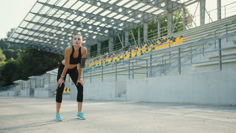 Joven-Corredora-Corriendo-Por-La-Mañana-En-El-Estadio,-Luego-Se-Detiene,-Respira-Y-Descansa-Por-Un-Minuto