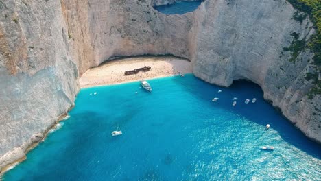 Dramatic-aerial-panorama-of-iconic-Shipwreck-Beach-full-of-people,-Zakynthos