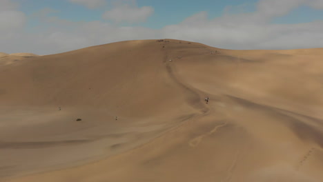 gente caminando por una duna de arena con tablas de arena