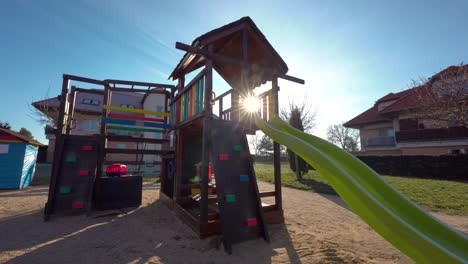 view of a colourful climbing frame in a playground in a built-up area backlit by the sun