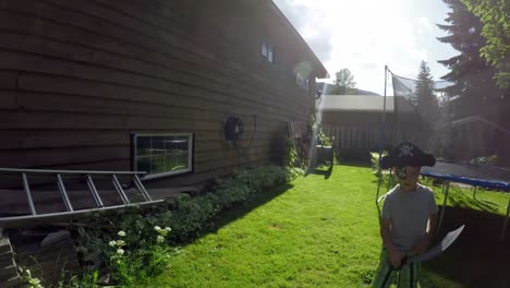 boy in pirate costume playing with sword in garden 4k