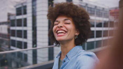 portrait of smiling young businesswoman posing for selfie standing outside modern office