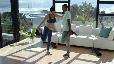 exercising together, pregnant woman and man stretching in living room with ocean view