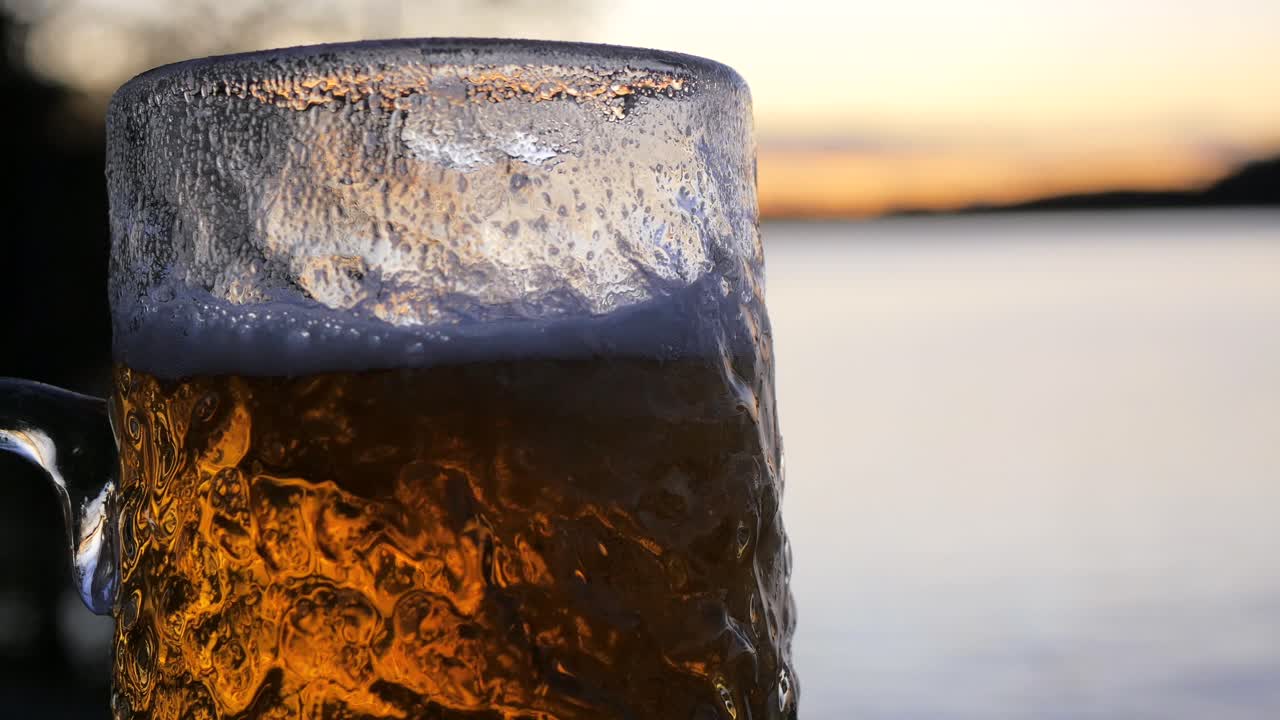 mientras el sol se pone en el archipiélago sueco, se vierte una cerveza lager fría en un vaso de cerveza ondulado