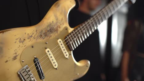 Person-holding-wared-old-heritage-electric-guitar-before-playing,-close-up-view