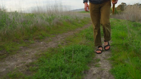 A-surfer-carries-his-board-as-he-hikes-down-to-a-remote-surf-spot-in-a-coastal-area-1