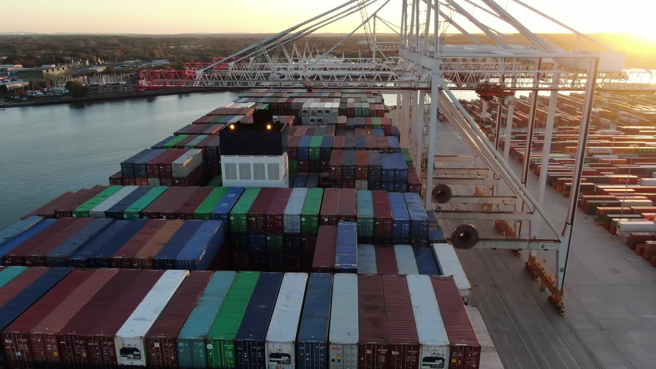 Top-down aerial drone shot flying over container ship in port unloading containers
