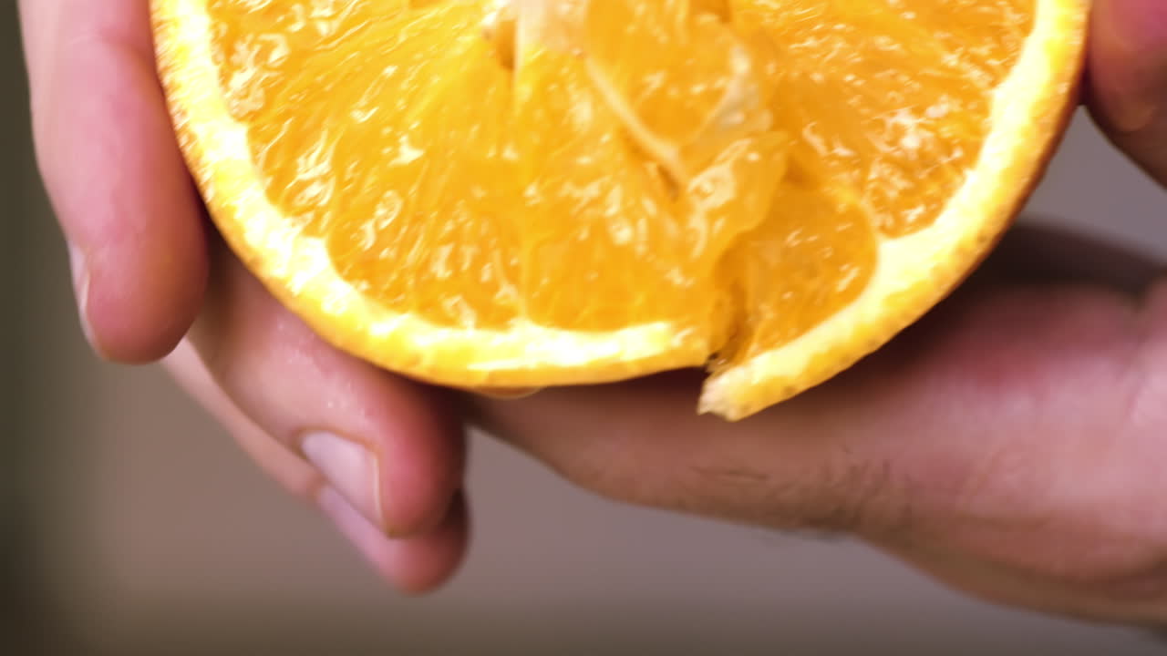 A woman squeezes juice from an orange. Slow motion