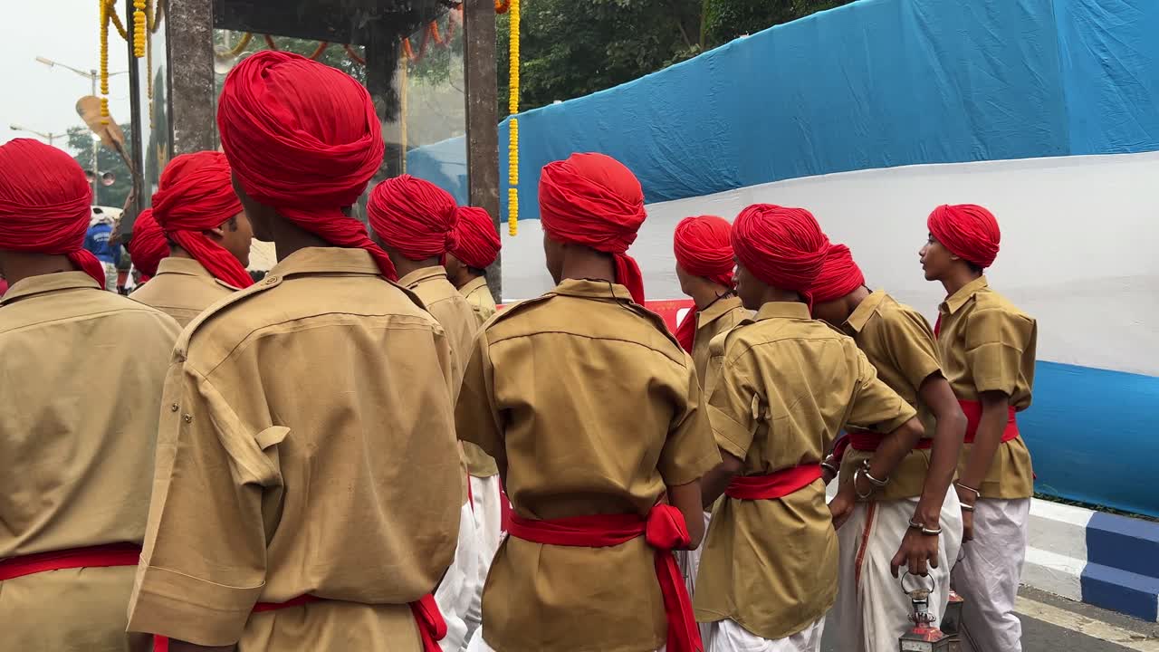 Men in Red Turbans and Tan Uniforms March in a Parade